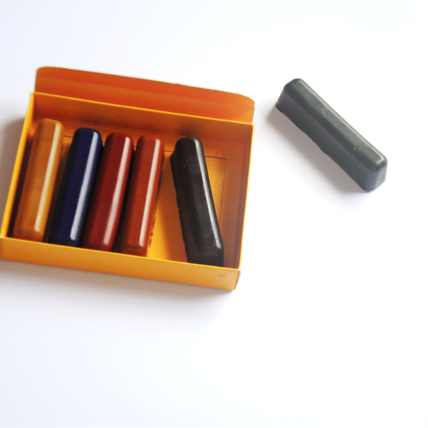 open box of 6 non-toxic handmade beeswax crayons with one crayon out of the box